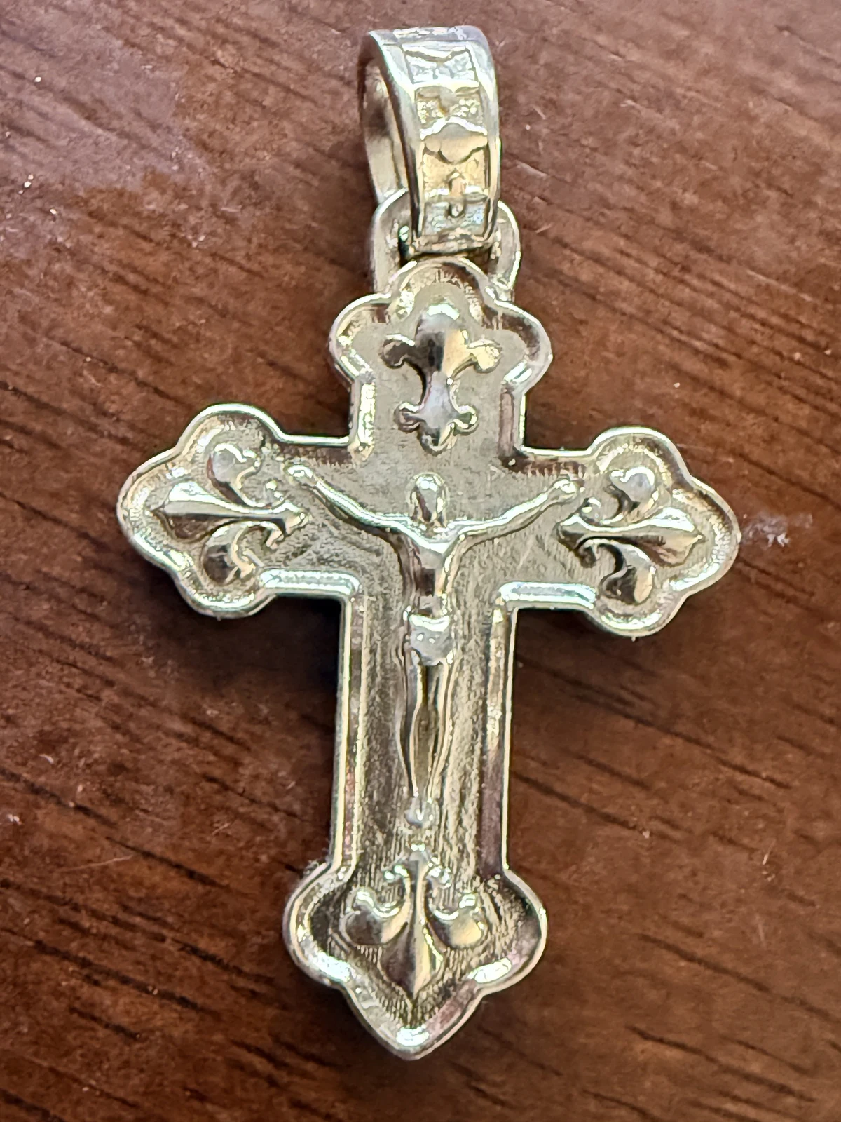 Sterling silver Orthodox Cross with fleur accents, photographed on wood