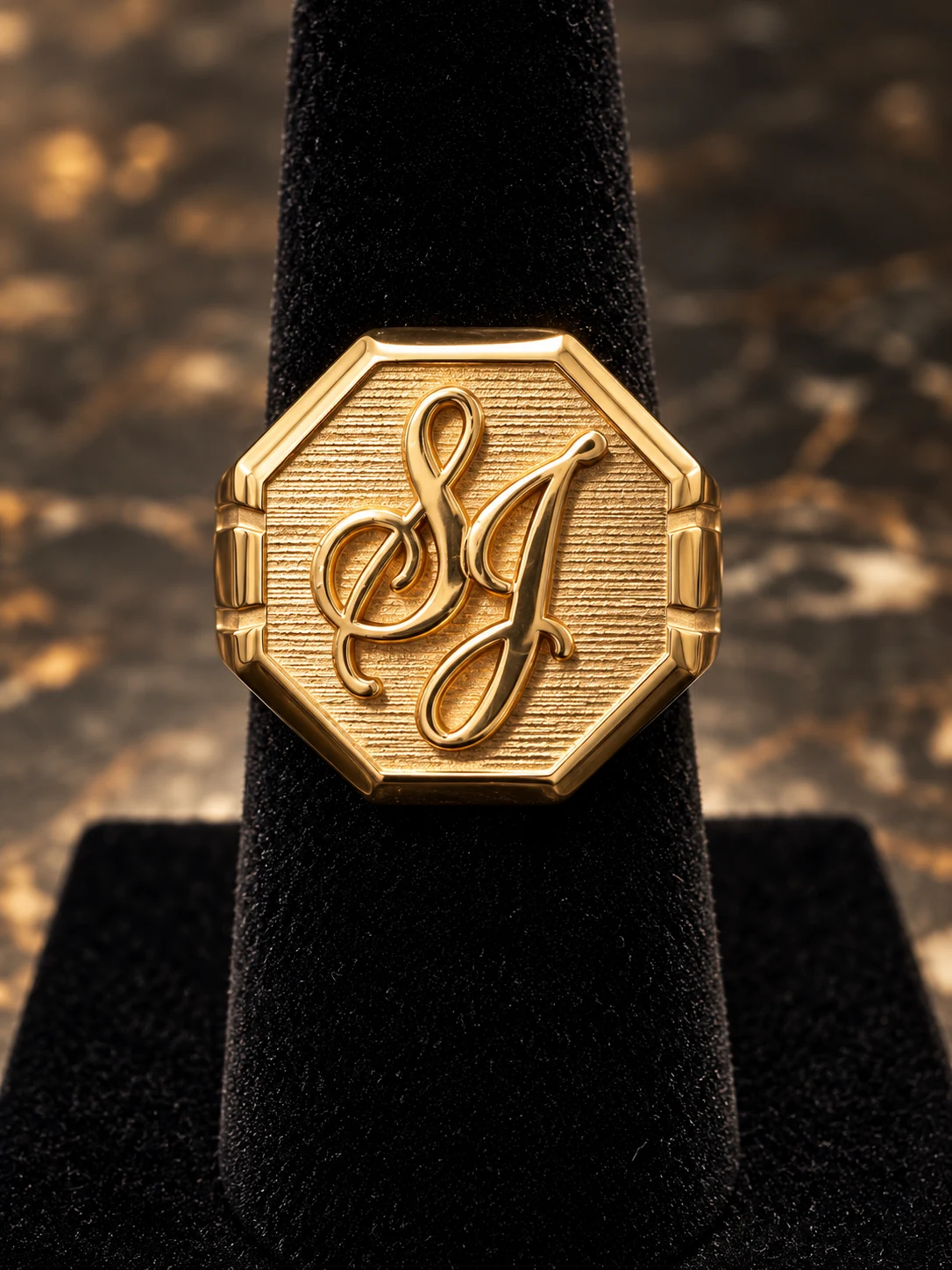 Gold octagonal signet ring with a raised SJ monogram and textured face