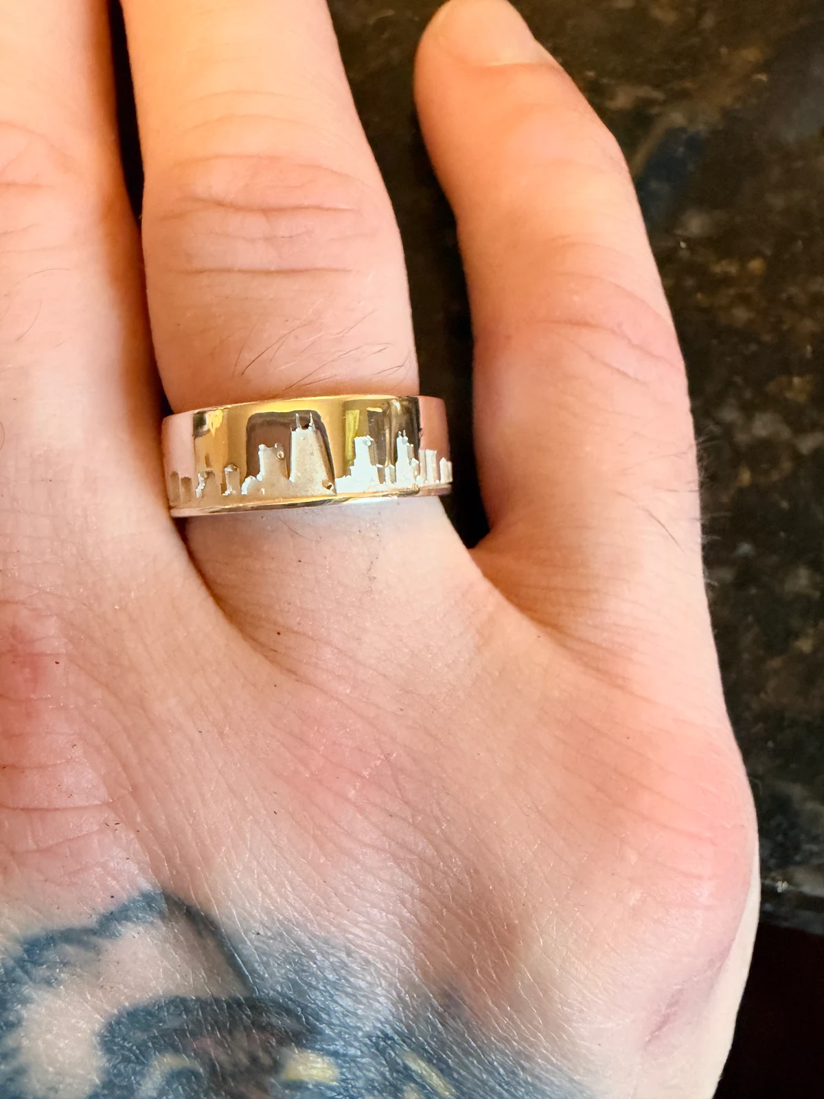 Skyline Ring worn on a finger, showing the Chicago skyline across the polished band